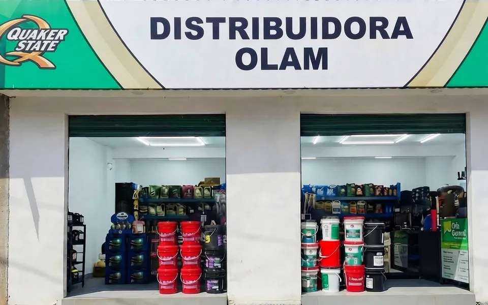 Fachada de Distribuidora OLAM en Nebaj, con aceites, filtros y repuestos en las dos vitrinas.