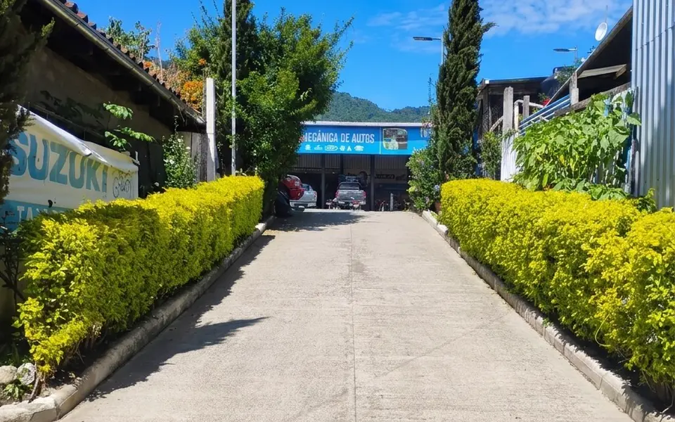 Entrada a los talleres de OLAM en Nebaj: el pasillo de acceso, con el rótulo de Suzuki a la izquierda.